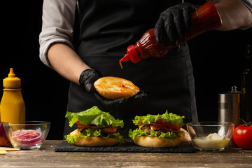 The chef is pouring a cupcake, burger sauce, on the background of the ingredients. Horizontal photo, Tasty and unhealthy food, fast food, homemade recipes, restaurant, catering, recipe book