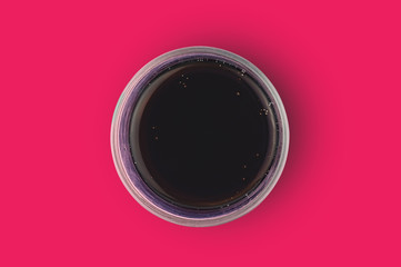 One full glass of aerated cola black color with bubbles in center of red table in cuisine. Top view. Rest concept