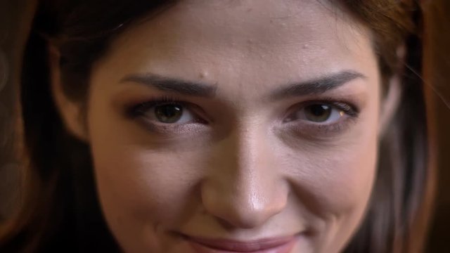 Closeup portrait of young beautiful caucasian female smiling and looking at camera with mistrust
