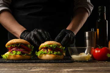 the chef prepares a burger, a hamburger. on a background with ingredients. Delicious and fast food, fast food. A menu, a cafe, fast food, catering, gastronomy
