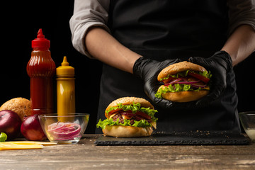 the chef prepares a burger, a hamburger. on a background with ingredients. Delicious and fast food,...