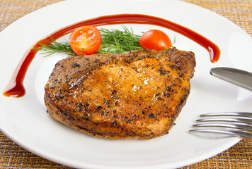 Steak meat with tomato and lettuce salad leaf and fork in a white plate