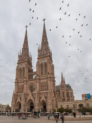  Church Our Lady of Lujan with partial view of the square and surrounded by birds on a cloudy...
