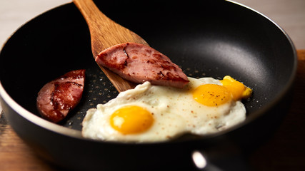 Fried eggs in a pan with sausage