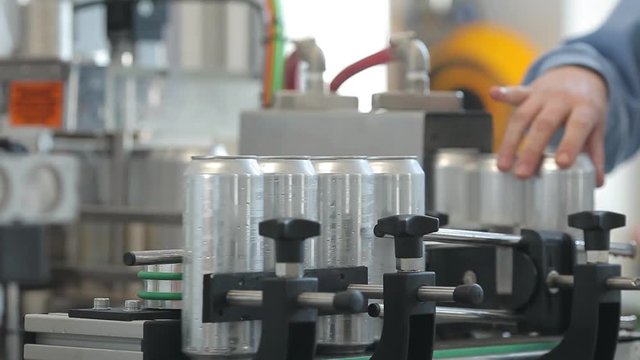 Conveyor for filling aluminum cans. Banks move along the conveyor and the person sorts them.