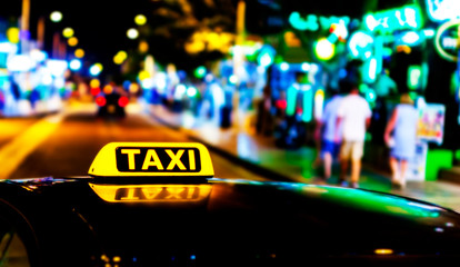Illuminated with yellow taxi taxi sign on a car roof at night.