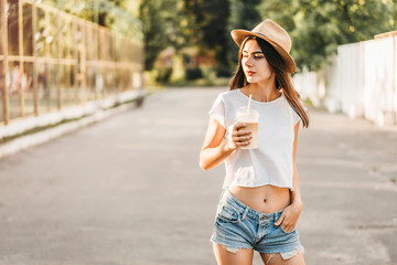 Brunette pretty tourist girl outdoor with cup of cold coffee.