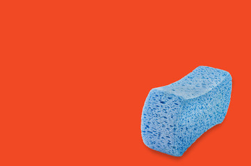 Blue porous sponge on orange background with copy space for your text