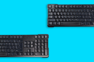 Two black plastic wireless computer keyboards on blue office table. Top view. Copy space for your text. Business concept