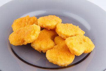 Chicken nuggets with cheese on a glass plate.