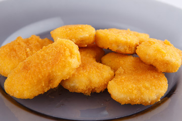 Chicken nuggets with cheese on a glass plate.