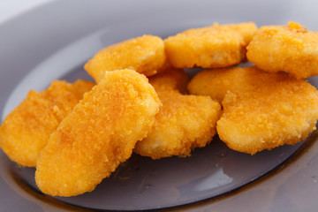 Chicken nuggets with cheese on a glass plate.