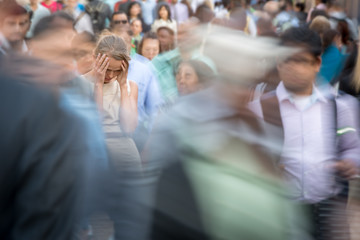 Depressed young woman feeling alone amid a crowd of people in a big city