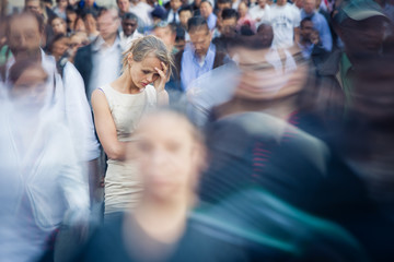 Depressed young woman feeling alone amid a crowd of people in a big city