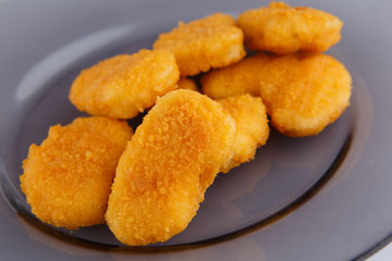 Chicken nuggets with cheese on a glass plate.