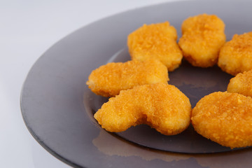 Chicken nuggets with cheese on a glass plate.