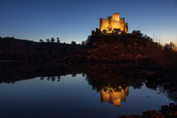 Naklejka na ściany i meble Almourol, Portugal - January 12, 2019: Almourol castle illuminated by artificial light at dusk with the reflection in the water of the Tagus river.