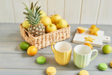 cups on the background of fruit, macaroons and lemons with limes on the table