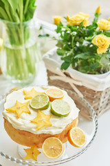 Naked cake with lemons and limes. Lemonade and flowers tulips on table. Mason jar glass of lemonade with lemons and straw. Copy space. Concept of spring and summer season. Healthy Food and Drink