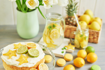 Lemonade and flowers tulips on table. Mason jar glass of lemonade with lemons and straw. Copy space. Fruits and macaroons on the table. The concept of spring and summer season.Healthy Food and Drink