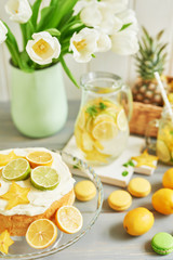 Lemonade and flowers tulips on table. Mason jar glass of lemonade with lemons and straw. Copy space. Fruits and macaroons on the table. The concept of spring and summer season.Healthy Food and Drink