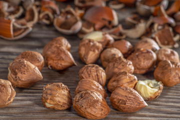 Peeled hazelnuts and nut shells on rustic background.