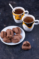 Delicious and fragrant coffee in the form of coffee, with grains of coffee, and small coffee cups on a black background