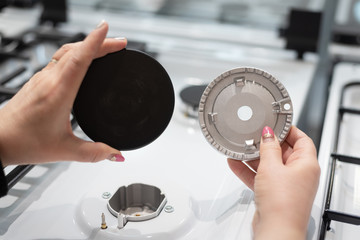 A young woman is choosing a gas stove for home kitchen.