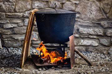 Traditional cooking chef in a cast iron cauldron. Food on an open flame. Cooking pan for many...