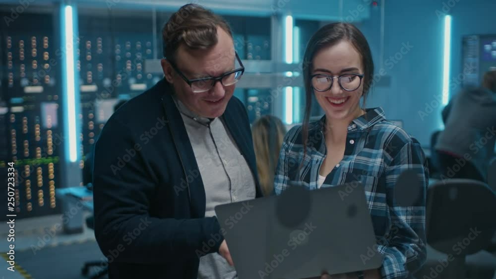 Poster Male IT Engineer and Female IT Programmer Talking, Holding Laptop. In the Background Technical Department with Server Racks and People Working. Concept: Artificial Intelligence, Machine Learning