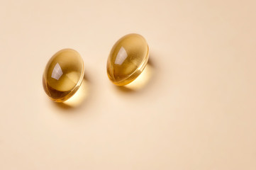 Two Yellow transparent pills on beige background.