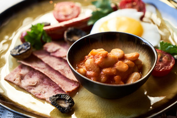 English breakfast with sausages, scrambled eggs, bacon, mushrooms and beans