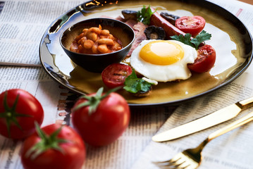 English breakfast with sausages, scrambled eggs, bacon, mushrooms and beans
