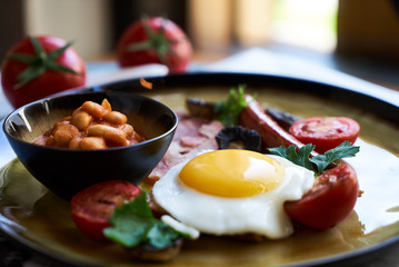 English breakfast with sausages, scrambled eggs, bacon, mushrooms and beans