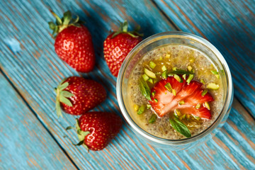 Fresh passion fruit cocktail with strawberries on wooden table background, close-up.