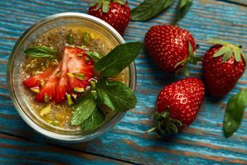 Fresh passion fruit cocktail with strawberries on wooden table background, close-up.