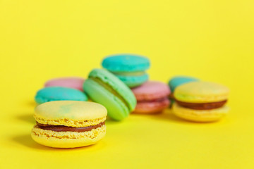 Sweet almond colorful unicorn pink blue yellow green macaron or macaroon dessert cake isolated on trendy yellow modern fashion background. French sweet cookie. Minimal food bakery concept. Copy space