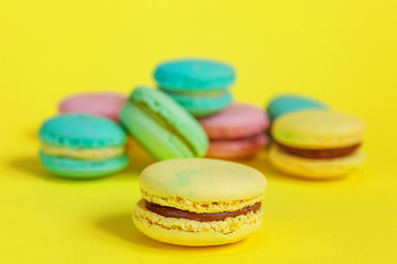 Sweet almond colorful unicorn pink blue yellow green macaron or macaroon dessert cake isolated on trendy yellow modern fashion background. French sweet cookie. Minimal food bakery concept. Copy space