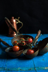 composition of cherry tomatoes inside ladles on wooden blue boards