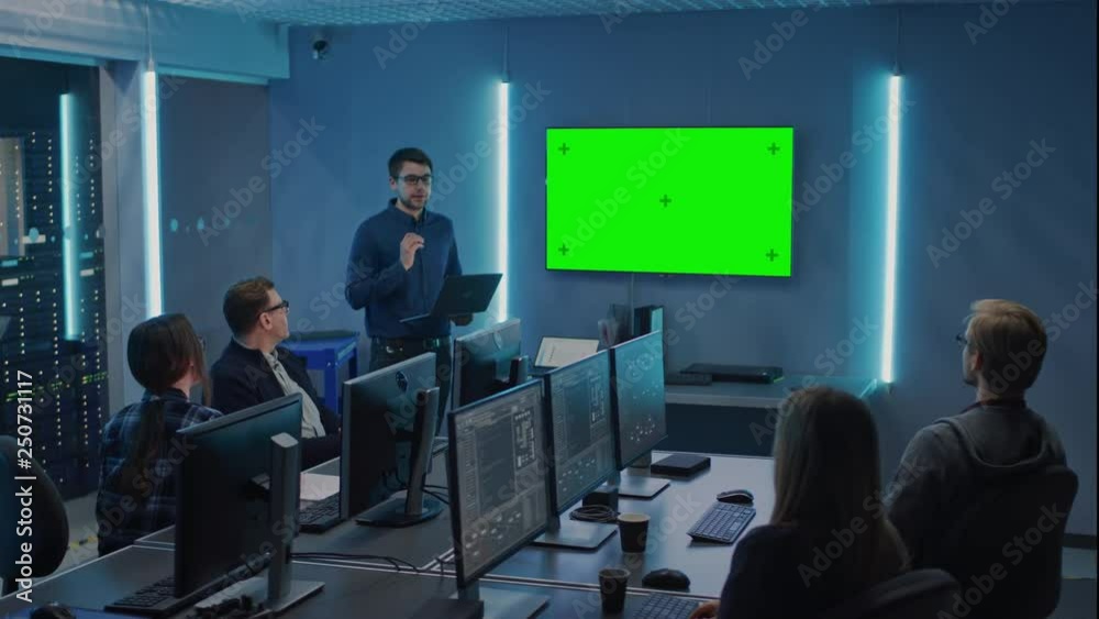 Poster Team of Professional IT Developers Have a Meeting, Speaker Talks about About New Concepts, On Wall TV has Green Mock-up Screen. Concept: Software Development, Deep Learning, Data Mining