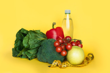 Fitness and healthy food diet concept. Vegetables and water on yellow background. Copy space.