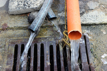 Three pipes draining water off in street sewer