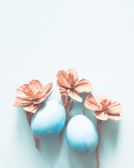 Easter blue eggs with decorative flowers on light background, top view, copy space	