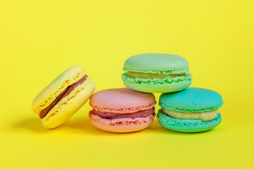 Sweet almond colorful unicorn pink blue yellow green macaron or macaroon dessert cake isolated on trendy yellow modern fashion background. French sweet cookie. Minimal food bakery concept. Copy space