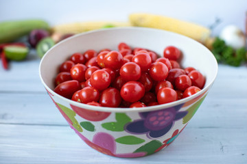 Cherry tomatoes in bamboo bowl on a wooden table.