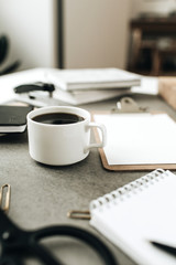 Coffee cup on home office desk workspace with stationery.