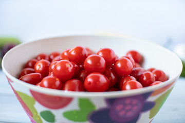 Cherry tomatoes in bamboo bowl on a wooden table.