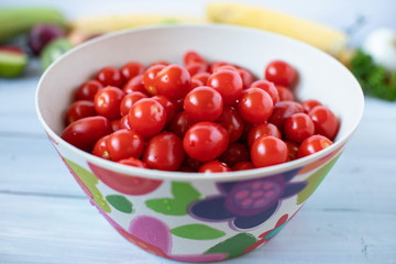 Cherry tomatoes in bamboo bowl on a wooden table.