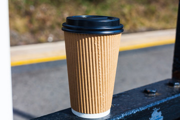 Espresso coffee for takeaway standing on the metal gate. Sunny day with espresso coffee in the plastic cup