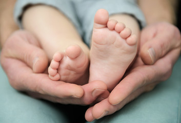 Baby's feet and the hands of an adult.